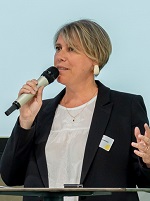 Portrait de Stéphanie Fournier qui parle dans un micro sur un fond bleu;